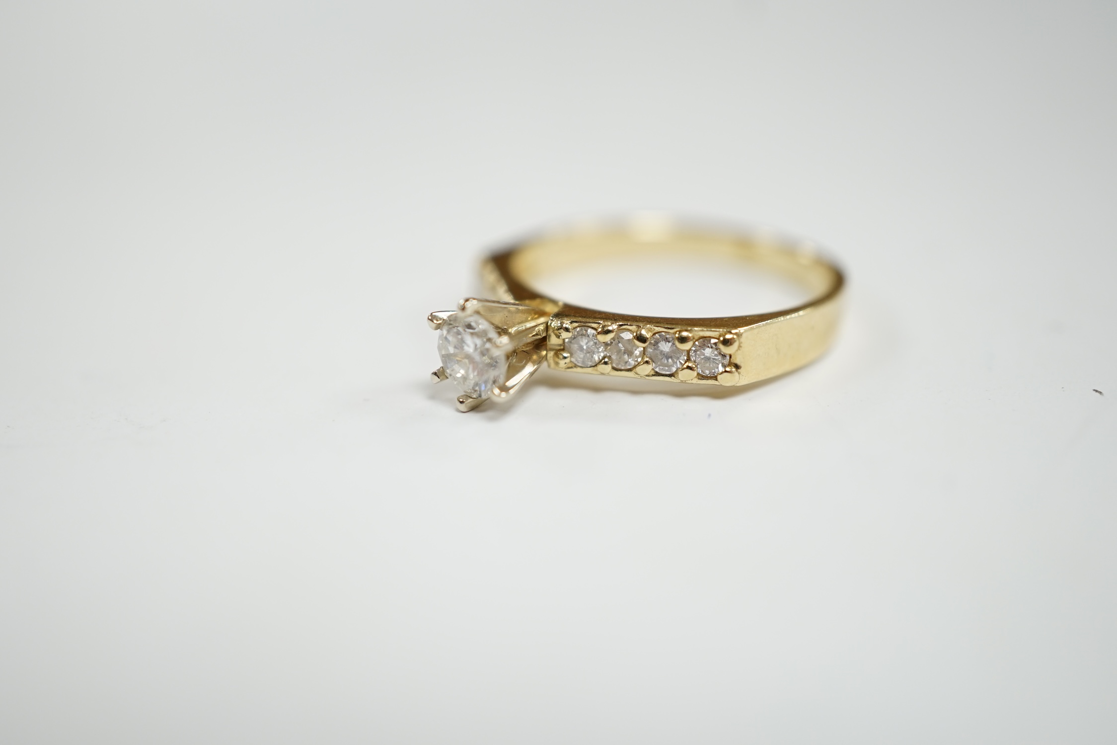 A modern 14k and single stone diamond set ring, with diamond chip set shoulders, size M, gross weight 2.7 grams.